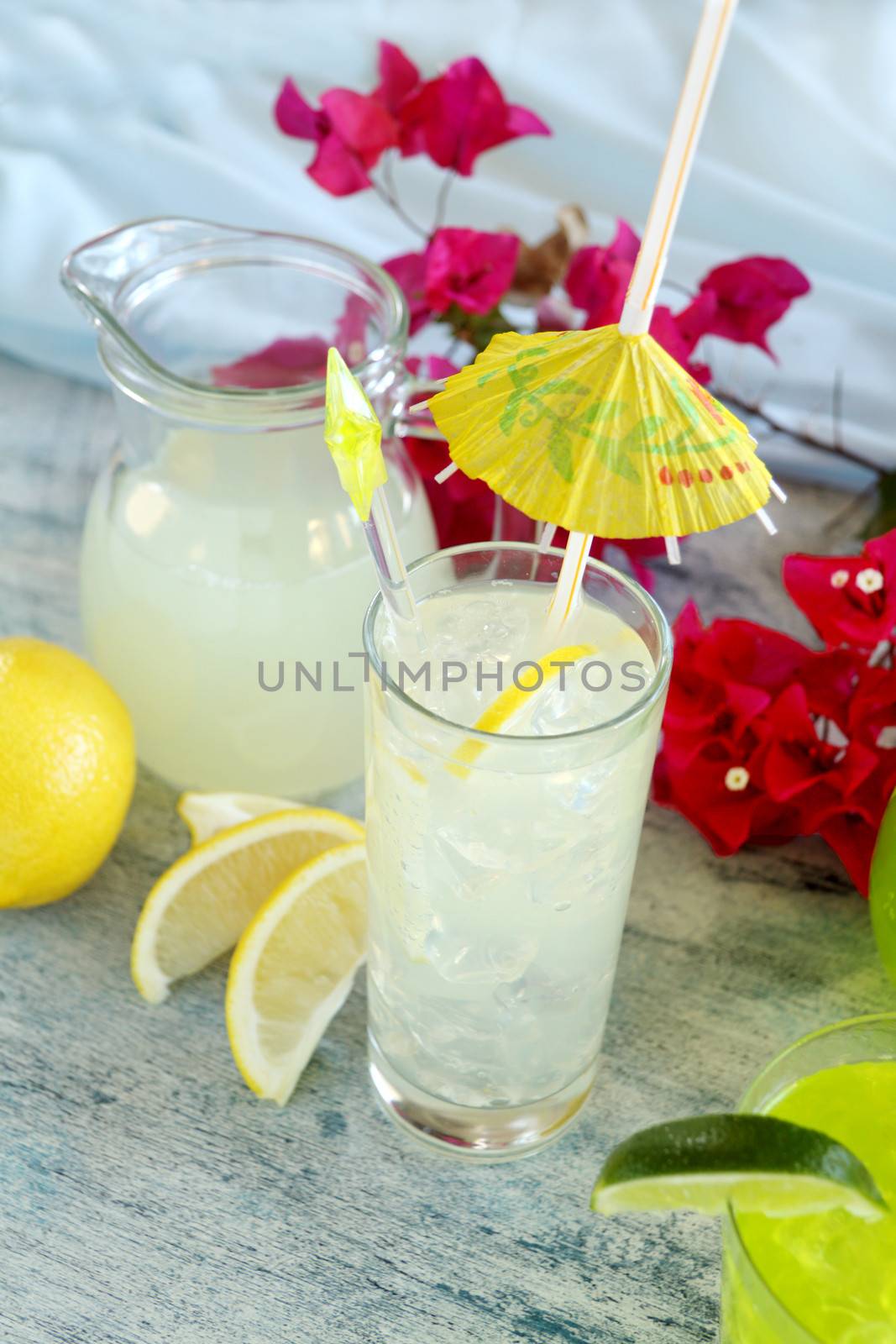 Ice cold lemon drink with cocktail umbrella and stirrer.