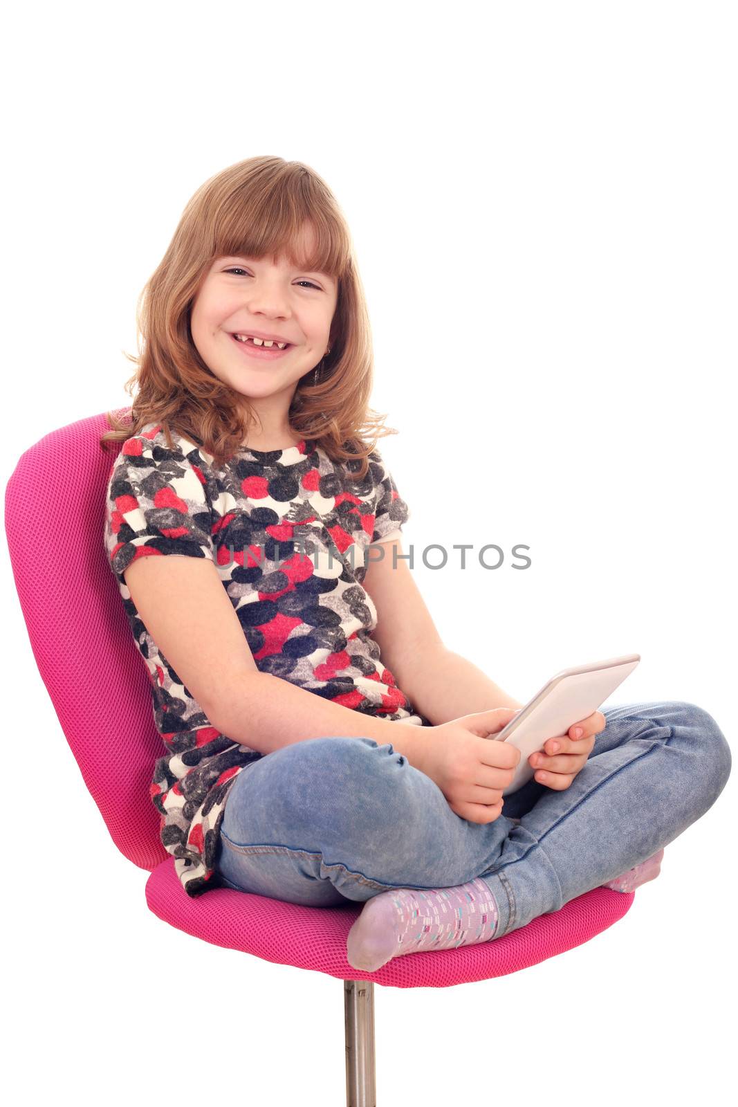 little girl sitting on chair and play with tablet pc by goce