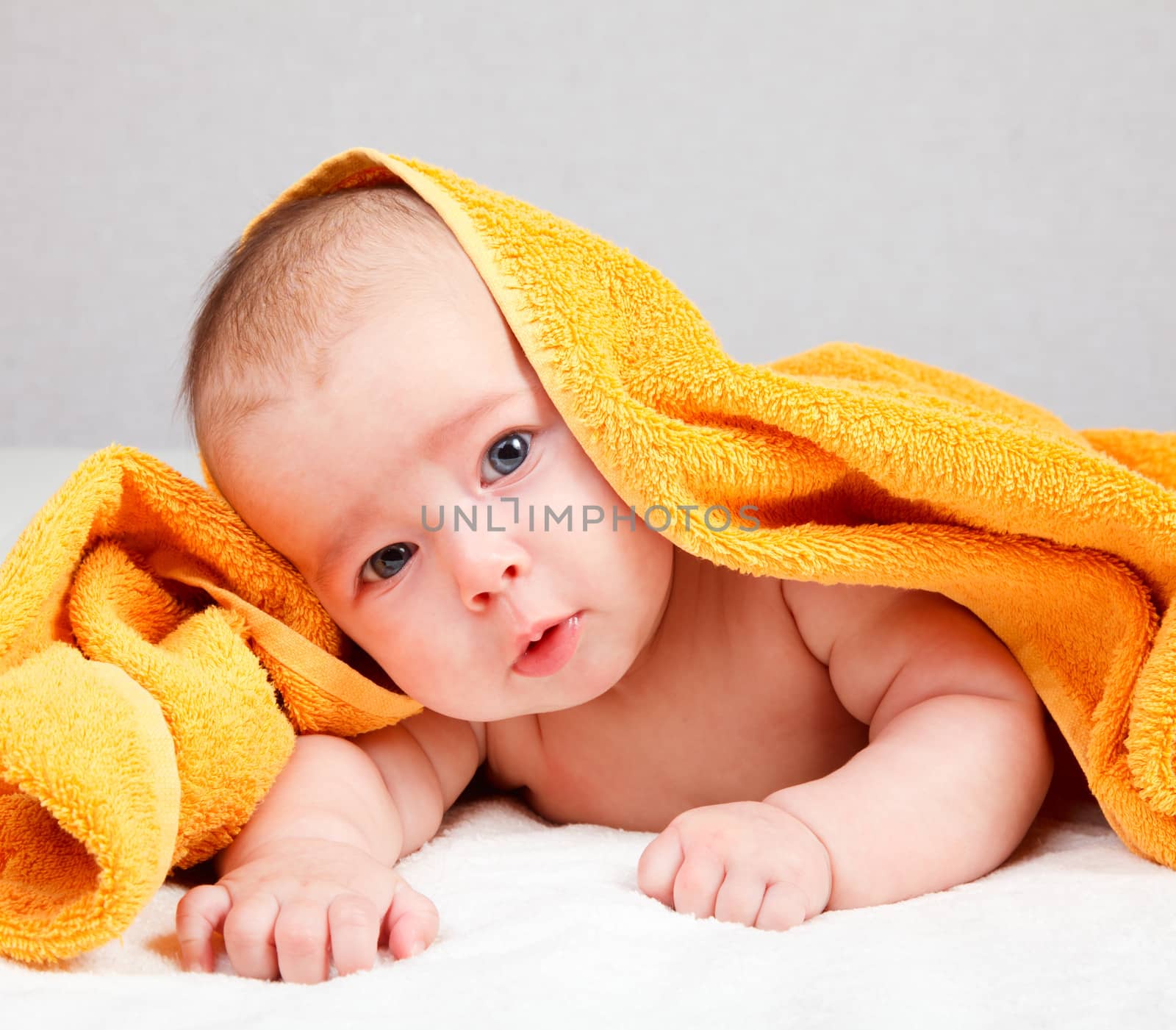 Little baby girl lying under yellow towel