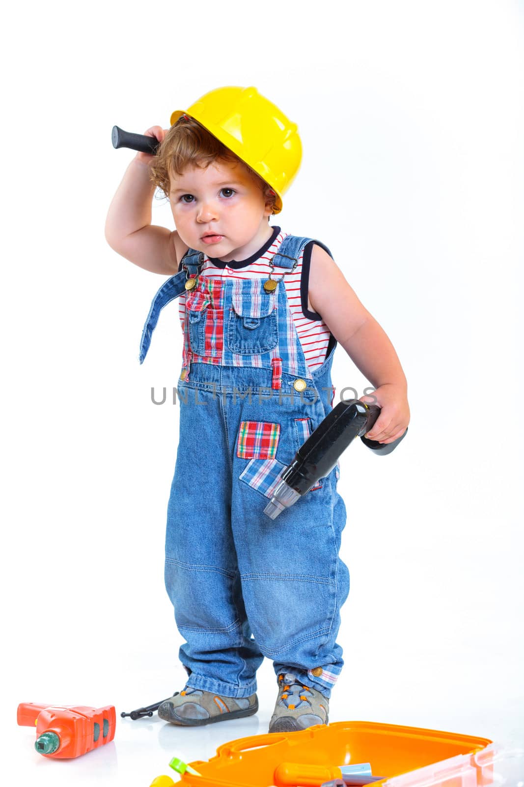 Little builder. Baby boy in a helmet plays in the builder with tools. Isolated over white.