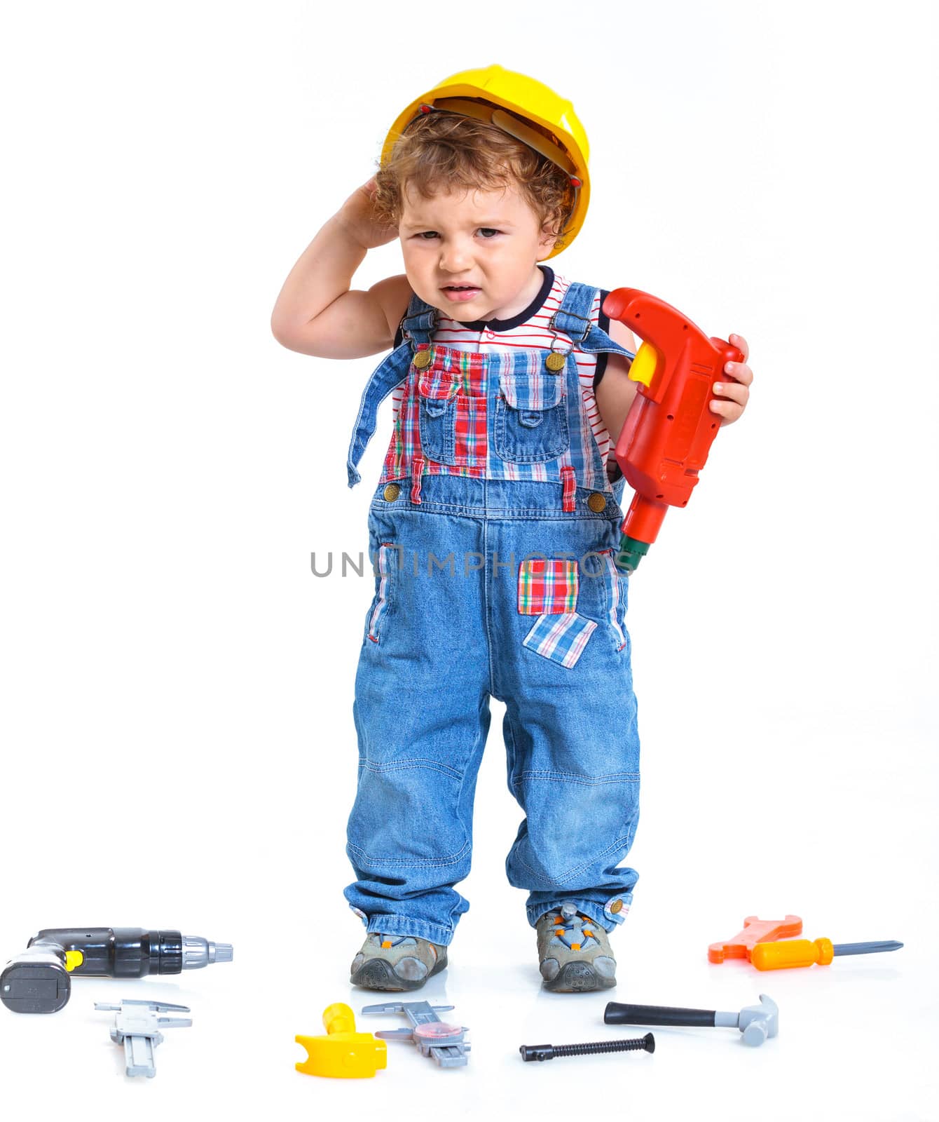Little builder. Baby boy in a helmet plays in the builder with tools. Isolated over white.