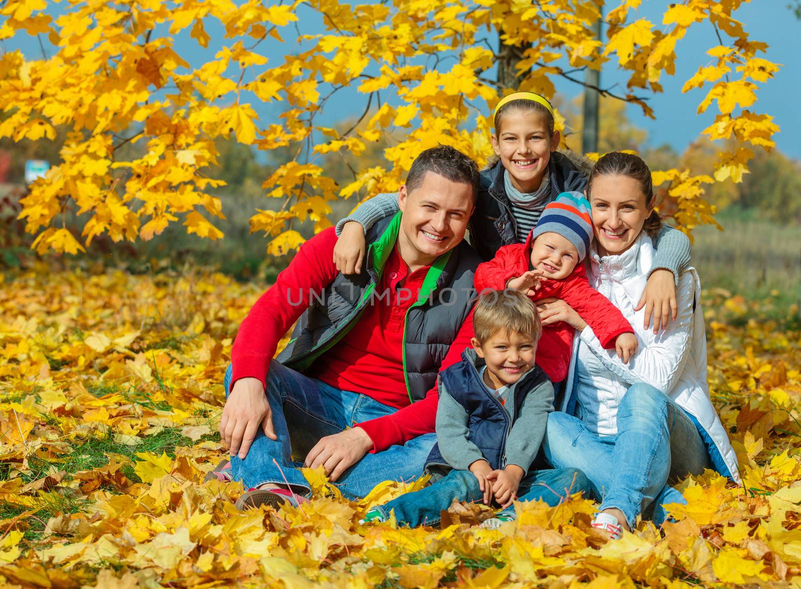 Happy family with three kids at beautiful autumn park