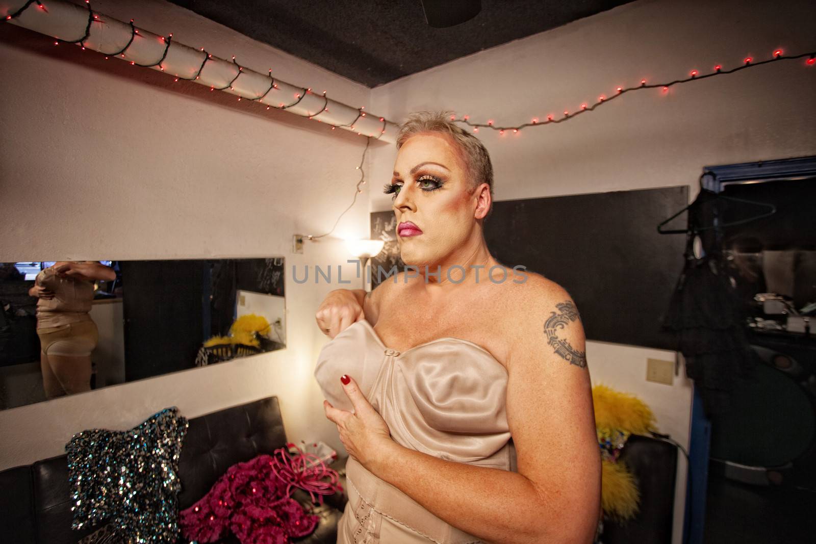 Serious cross dressing person in backstage fixing bra