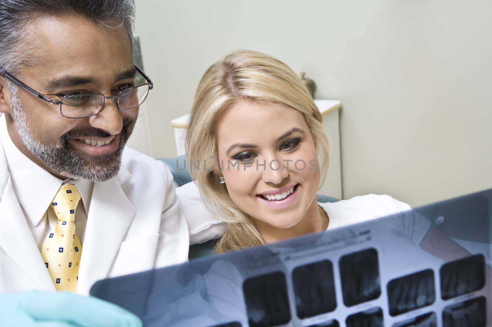 Happy dentist with female patient looking at x-ray report at clinic by moodboard