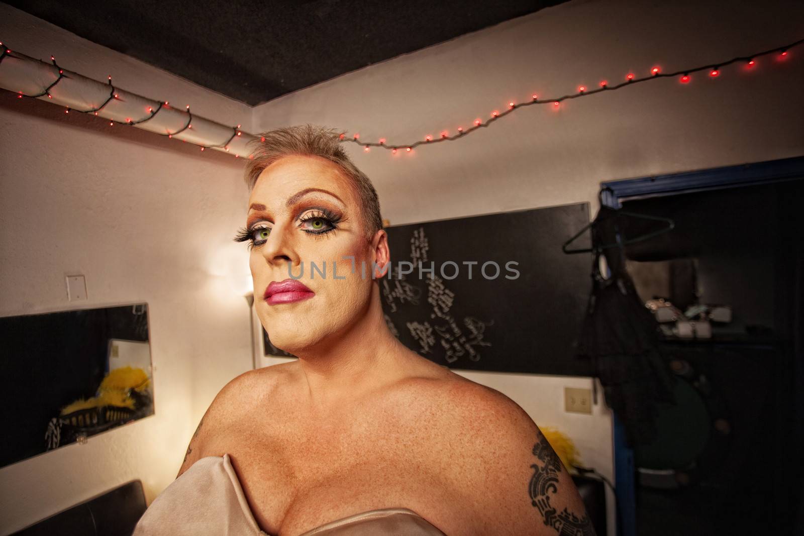 Serious drag queen with bra and tattoo in dressing room