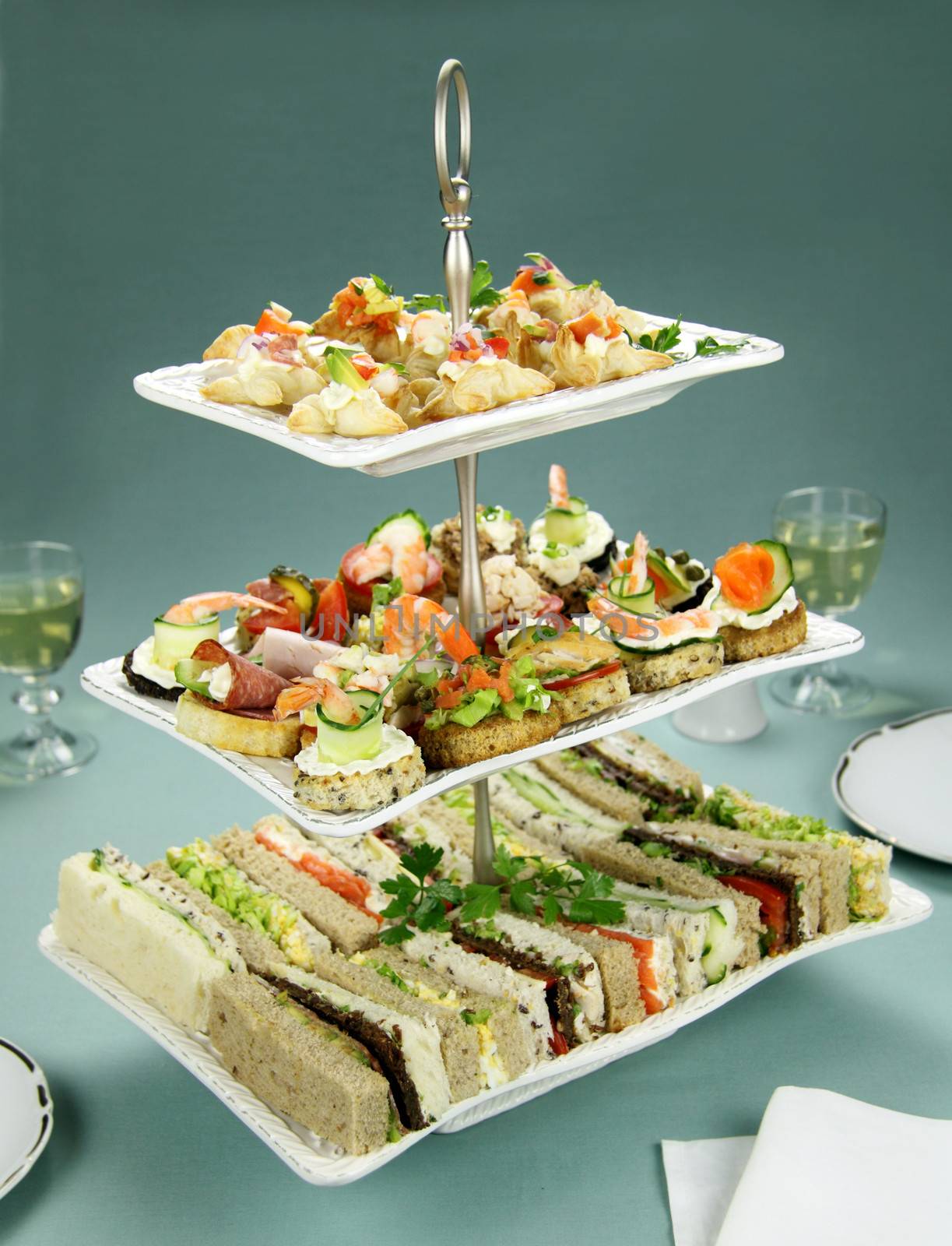 Delicious assorted finger food and sandwiches on a three tier stand.