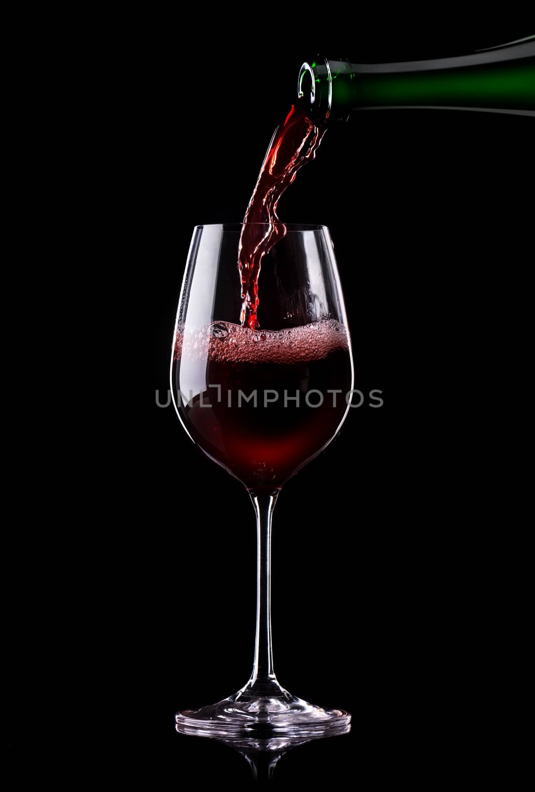 Red wine being poured into a glass on a black background