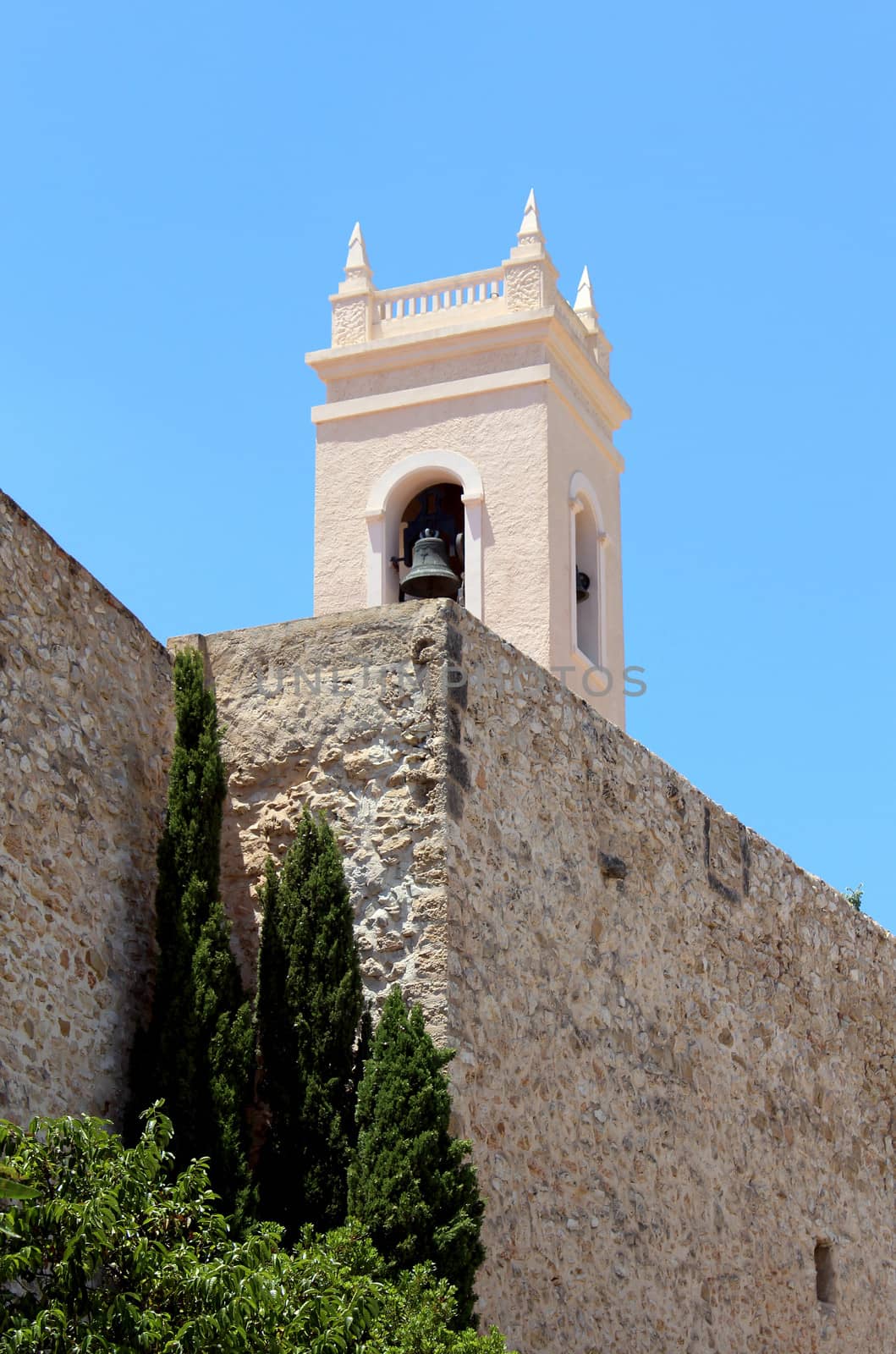 Torreon de la Pena ancient fortified wall and the tower bell of parish church Nuestra Senora de las Nieves, located in the Calp old town. Spain