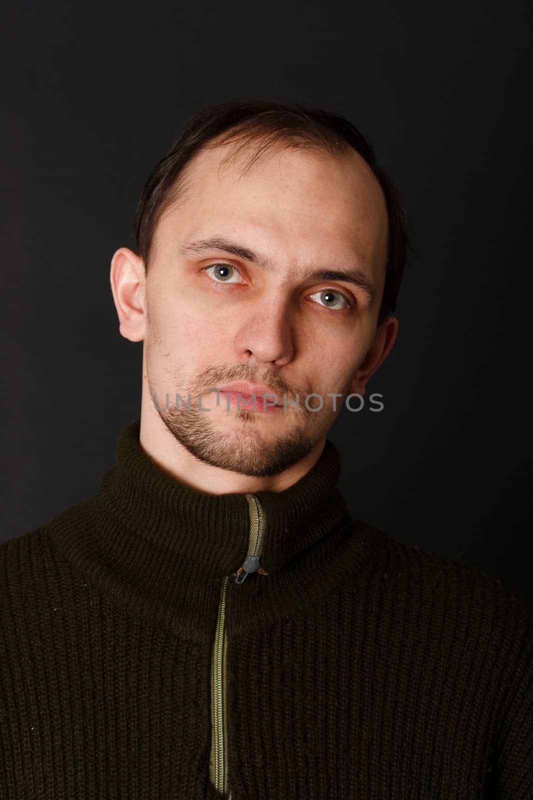 young man in an old sweater on a dark background. studio portrait