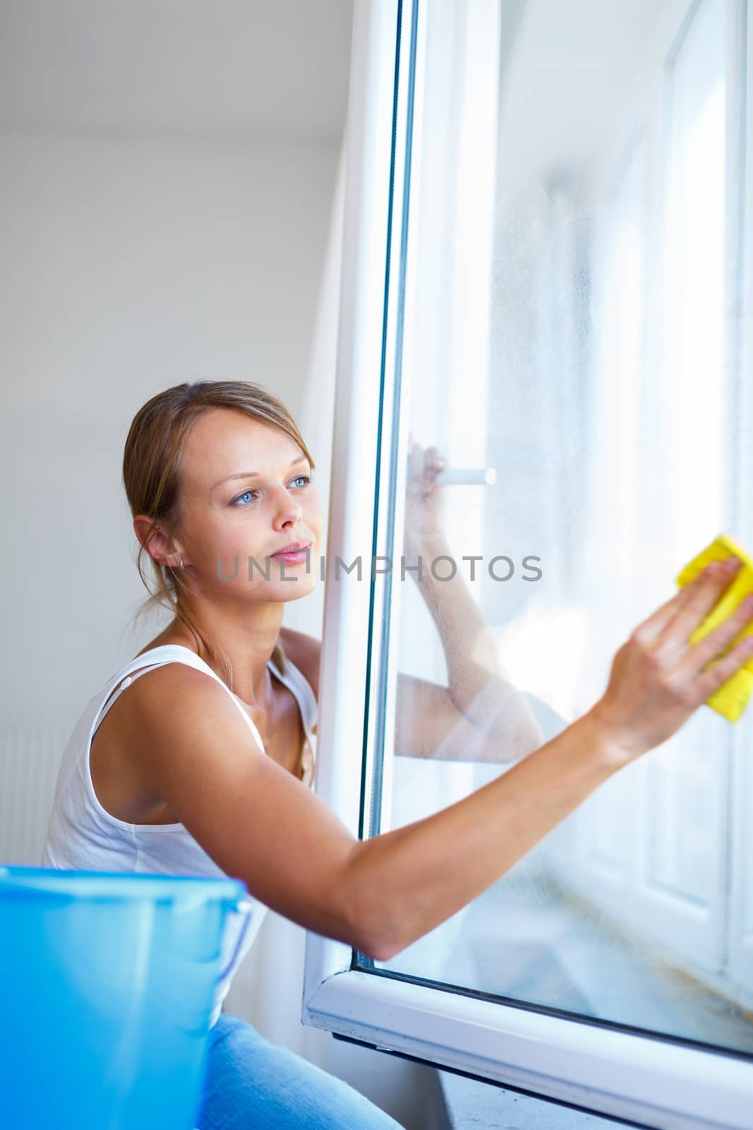 Pretty, young woman doing house work - washing windows (shallow DOF; color toned image)