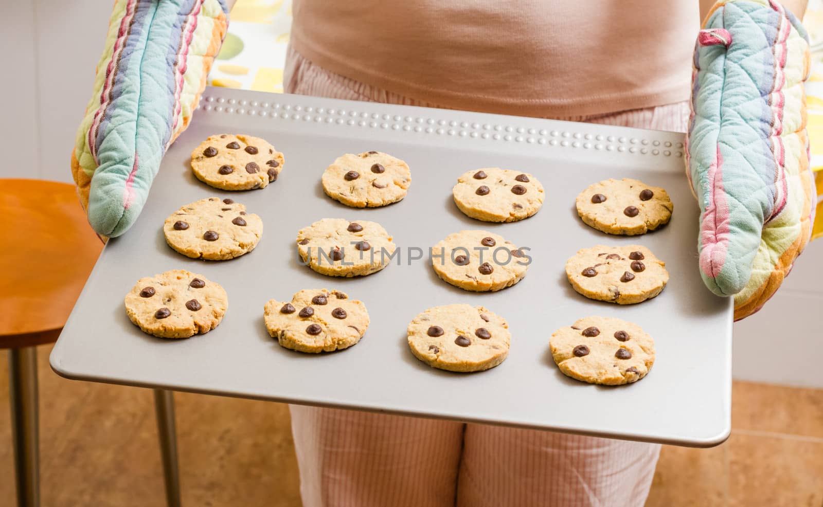 Woman holding a tray with homemade baked cookies with colorful kitchen gloves