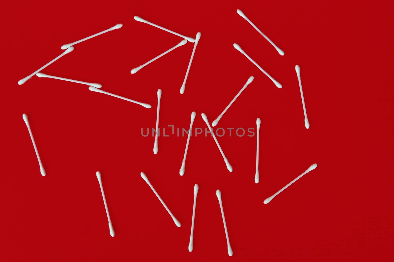 Ear buds white cotton swabs on red background.