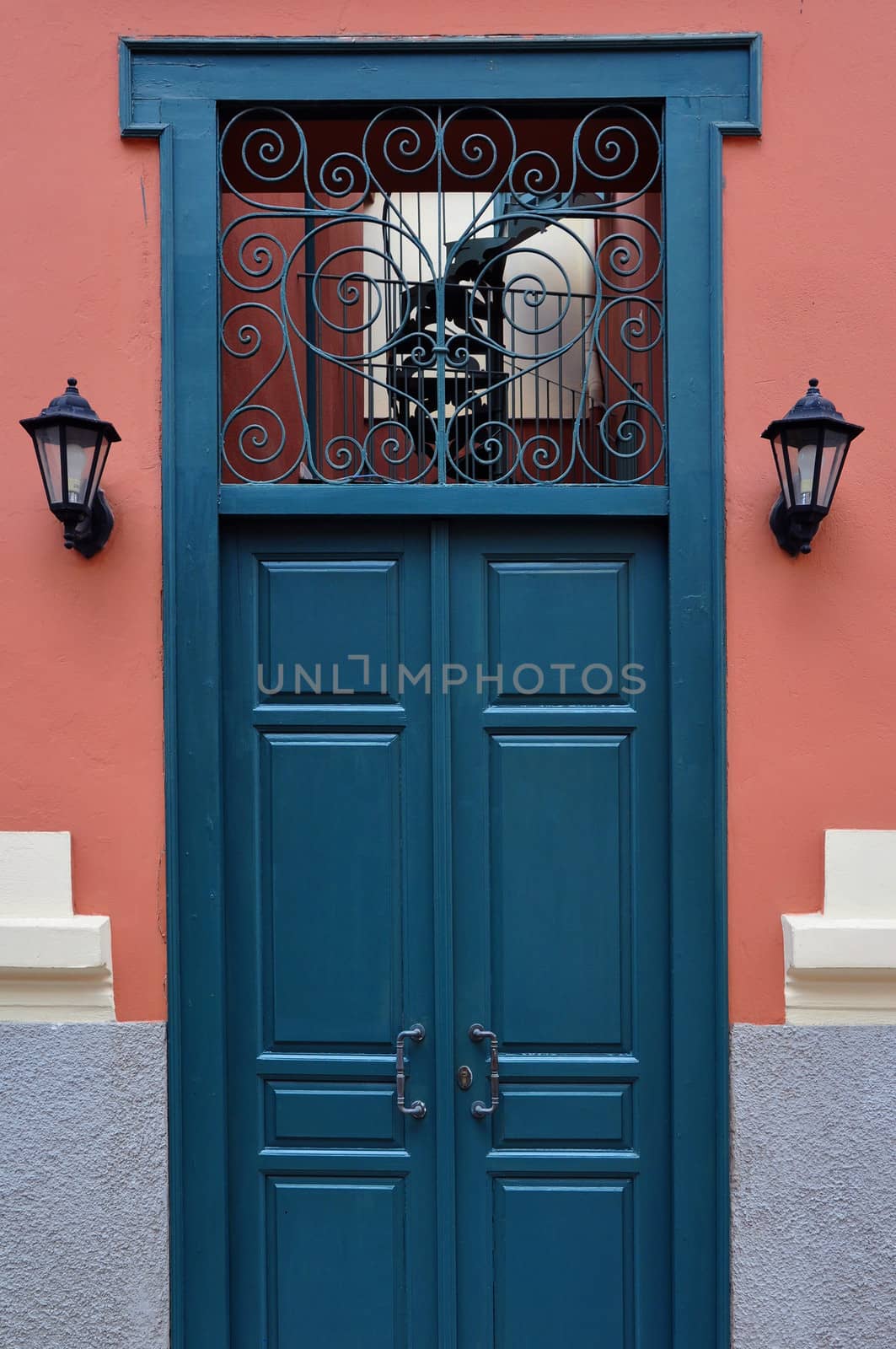 Blue wooden door with antique wrought iron pattern. Architectural detail.