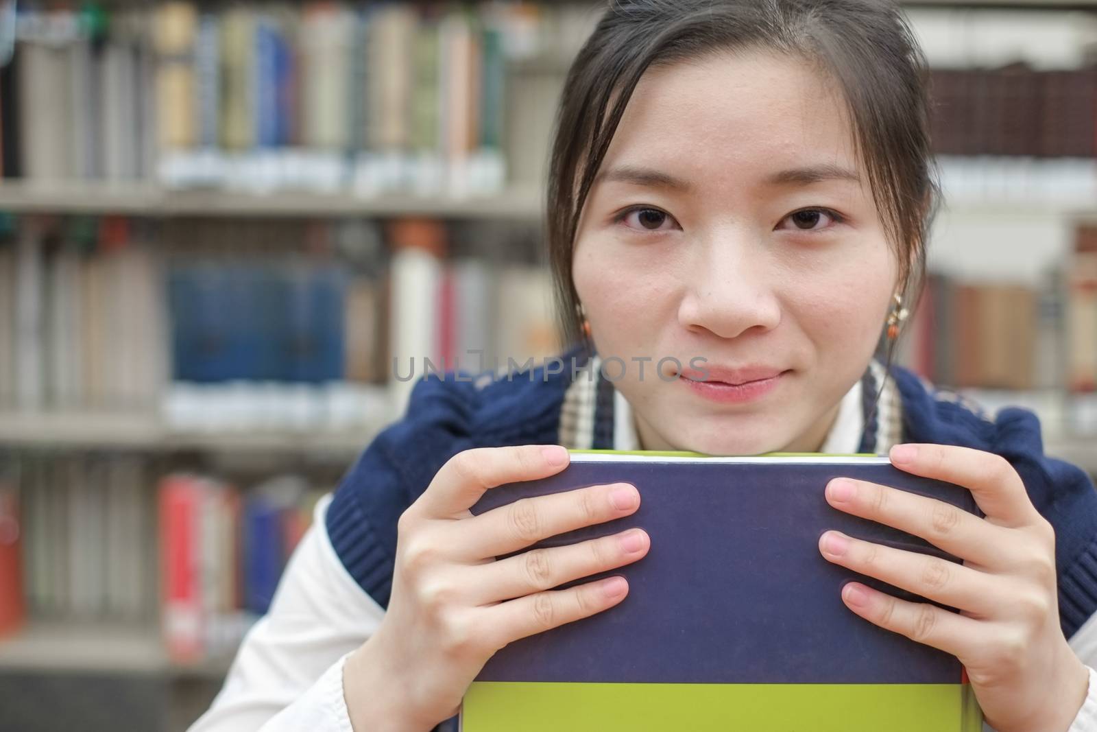 Student resting her chin on textbook by IVYPHOTOS