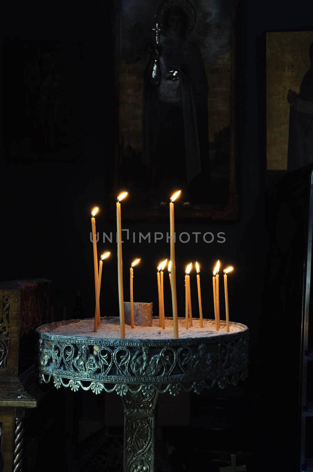 Vintage byzantine manouali candle stand in dark orthodox church interior.