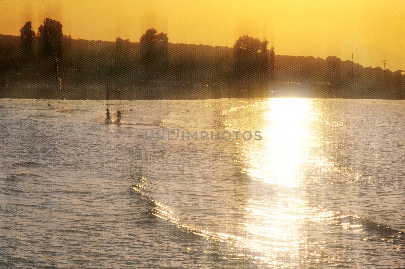 Children playing at the beach. Sunset light leaking on sea water vintage style photo composite.