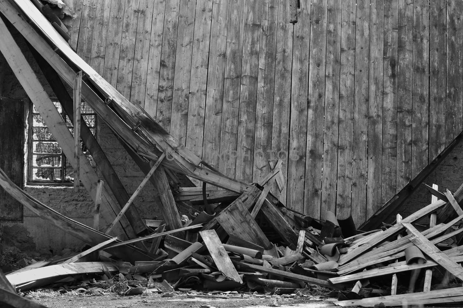 Collapsed roof wooden wall and broken window in abandoned house interior.