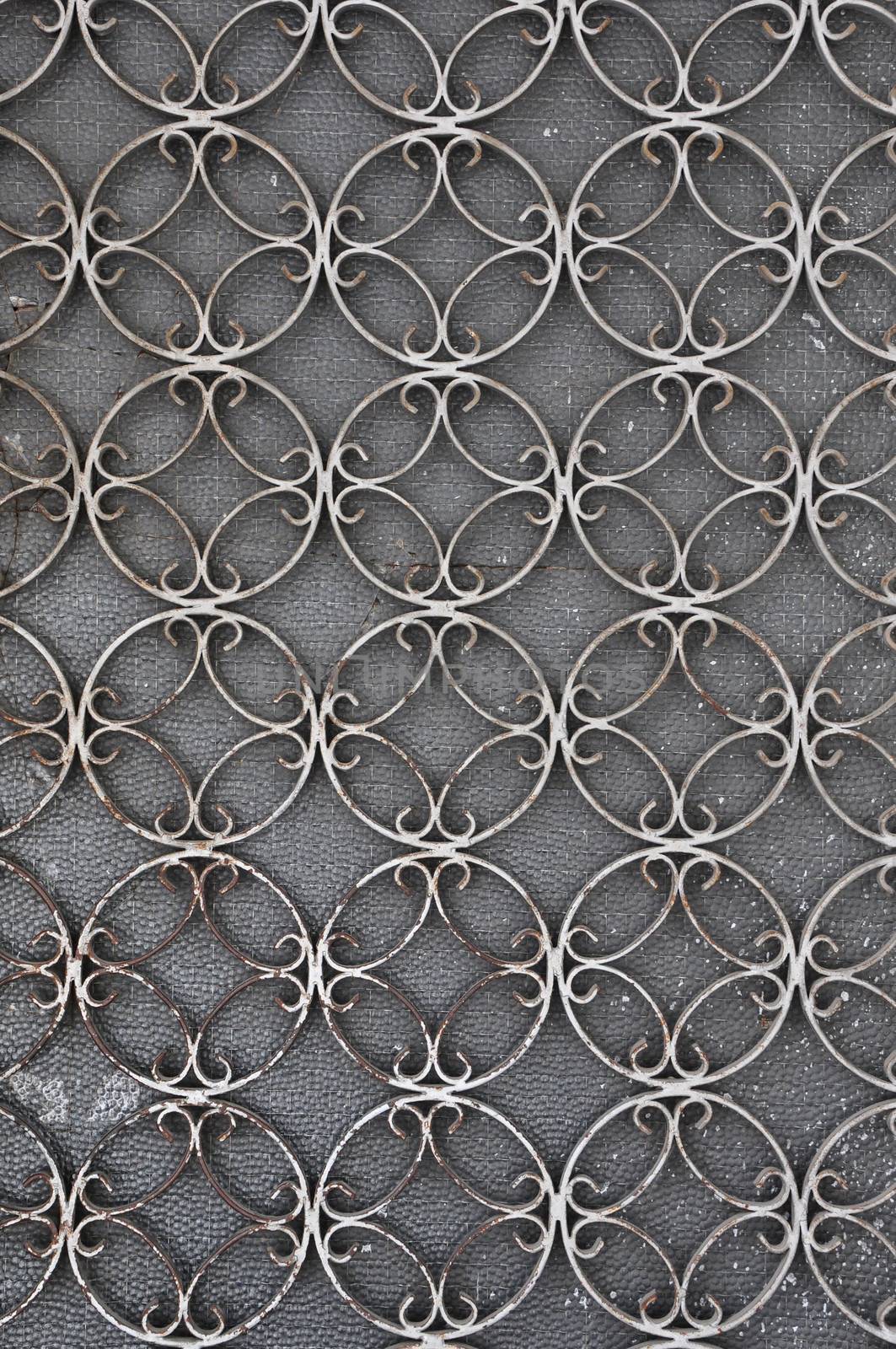 Vintage iron door frame with circles pattern detail and stained glass background.