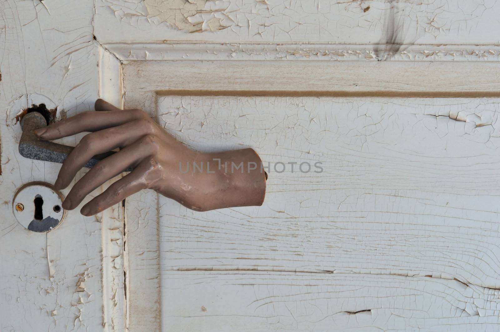 Doll hand opening a closed door in haunted house.