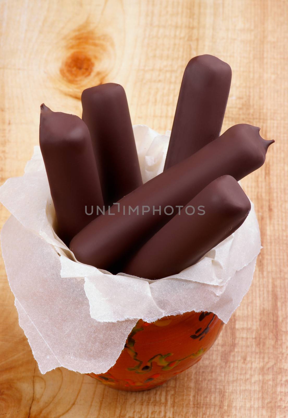 Ice Cream Sticks Glazed in Dark Chocolate in Bowl on Wooden background