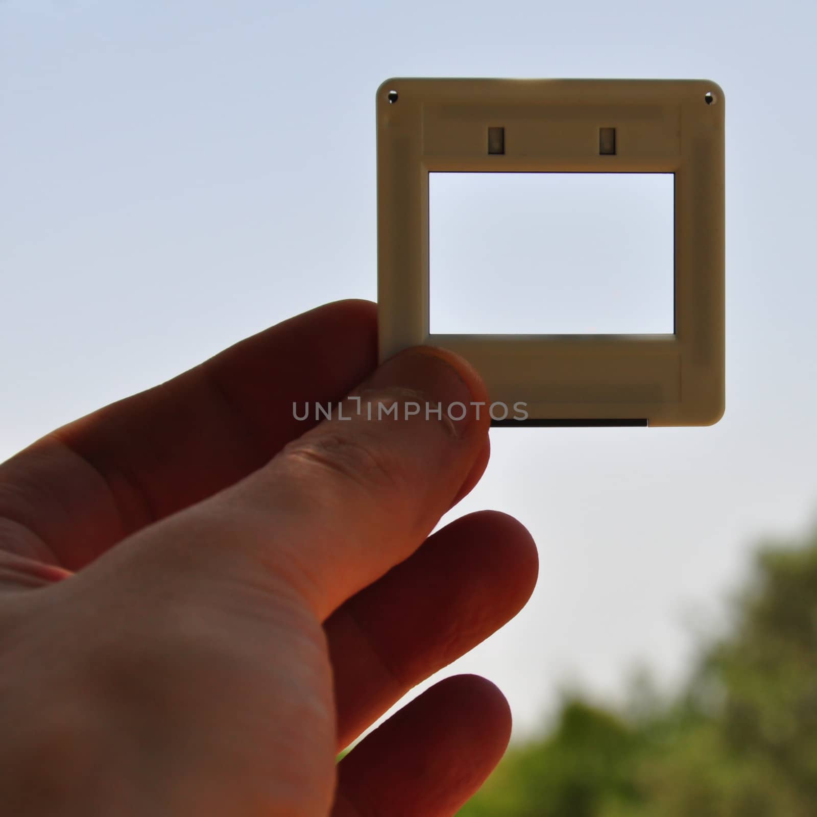 Hand with blank photographic slide picture frame. Place your own image or text.