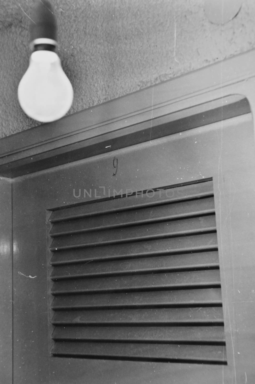 Light bulb and basement door. Black and white old grainy photo with dust and scratches.