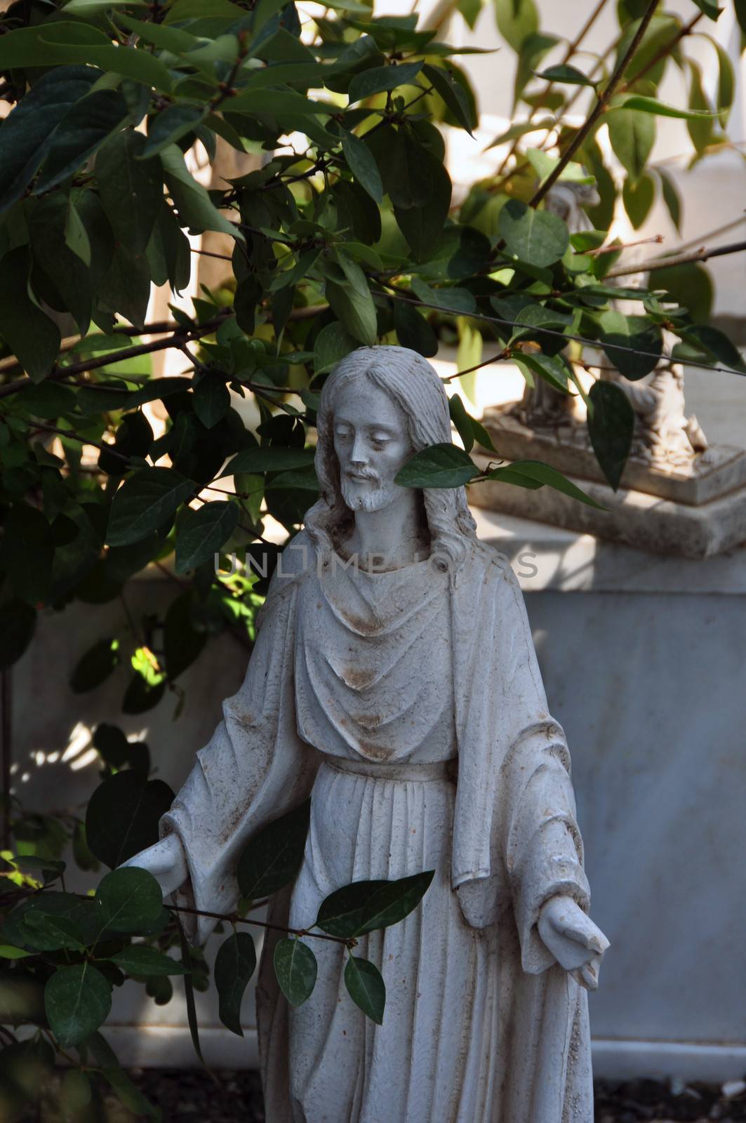 Jesus Christ marble funerary statue among leaves.