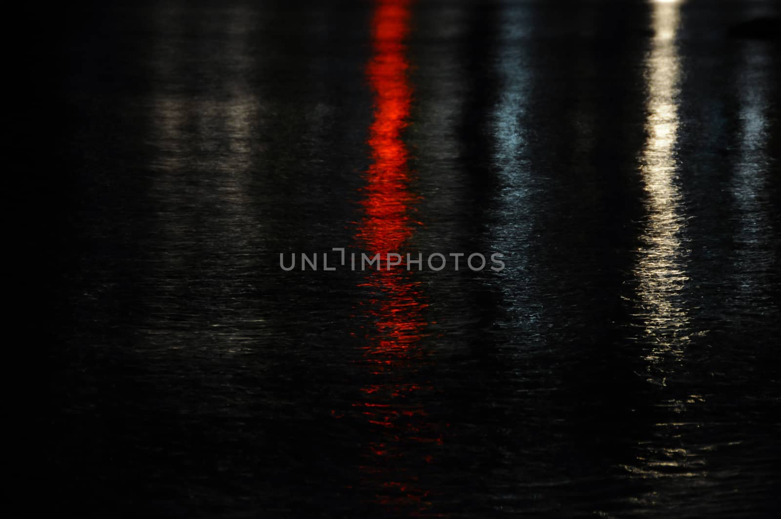 Colorful city lights reflected on dark sea water. Night abstract background.
