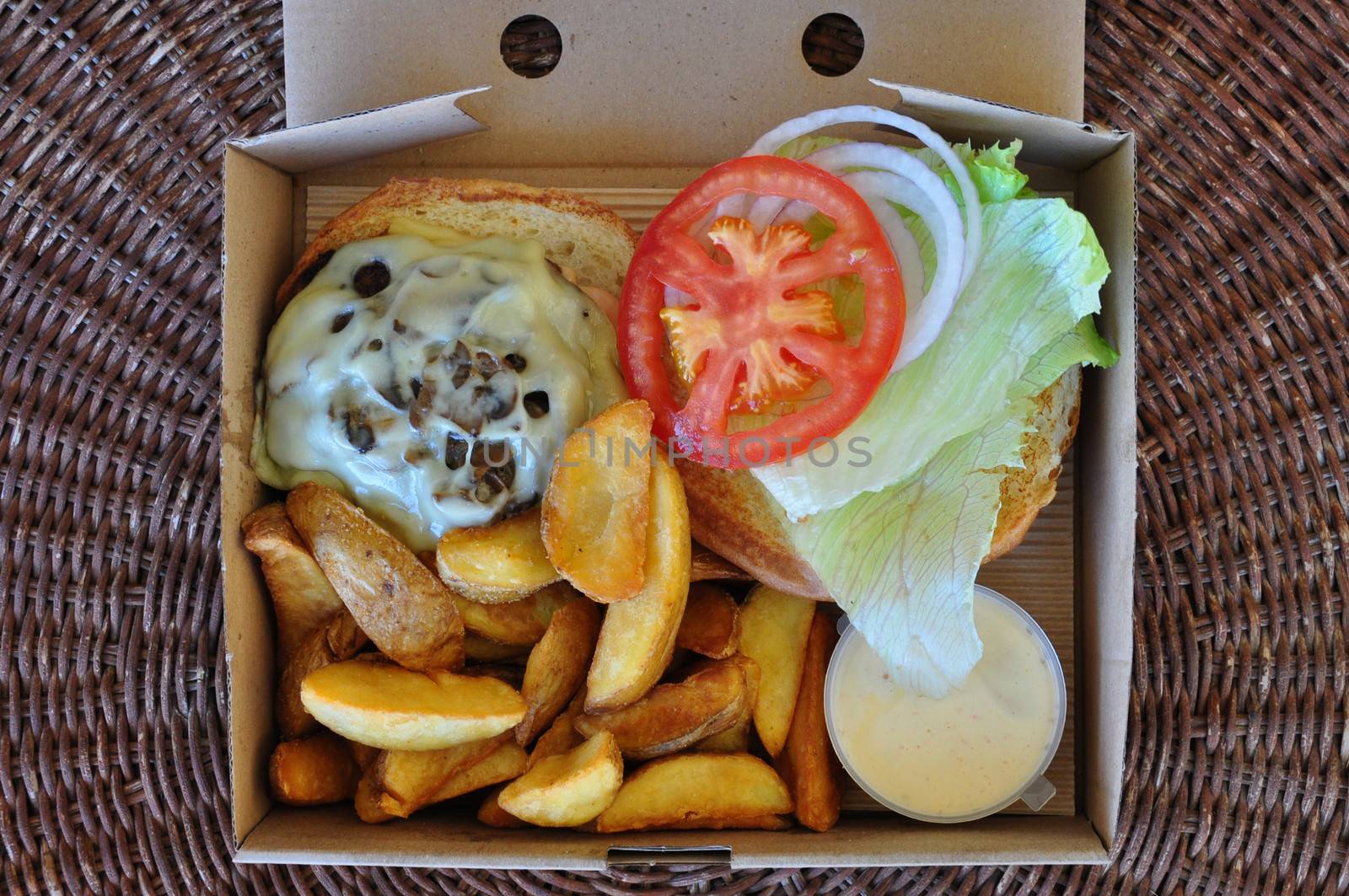 Burger with fries and melted cheese mushrooms. Takeaway food in packaging.