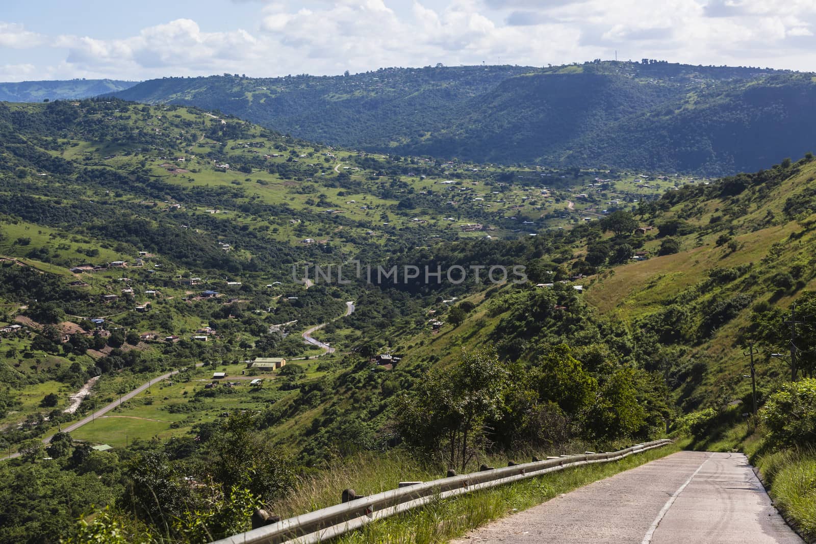 Steep concrete road in and out of  green valley landscape.