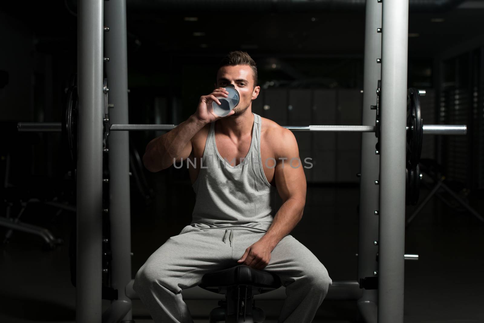 Healthy Young Man Resting And Drinking Water At Gym