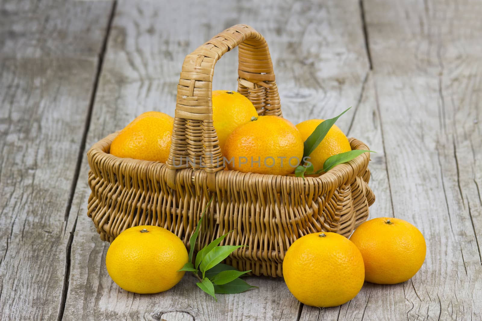 fresh tangerines in a basket on old wooden background