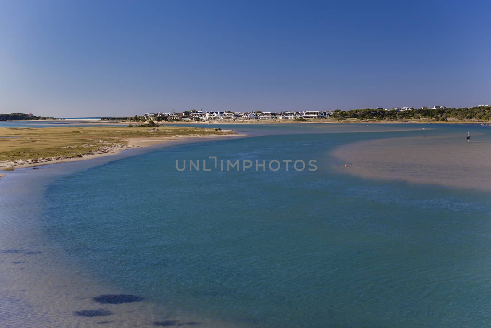 Blue river channels through sandbanks towards distant ocean