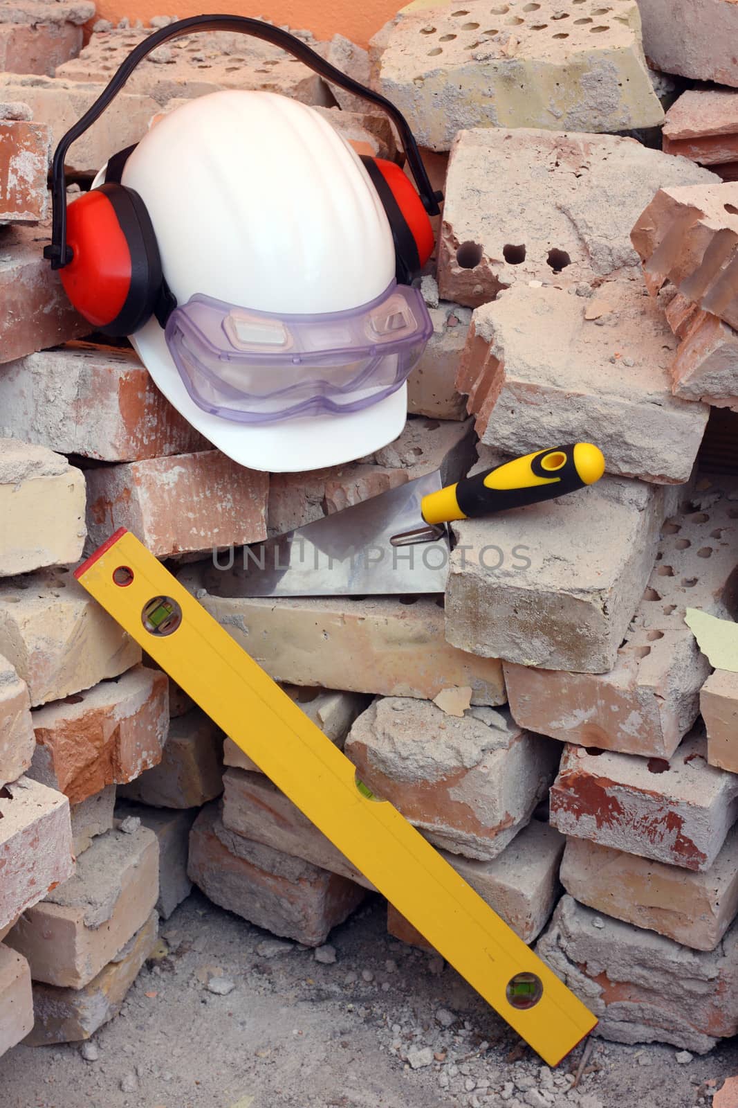 Bricks, trowel, level and helmet on work place 