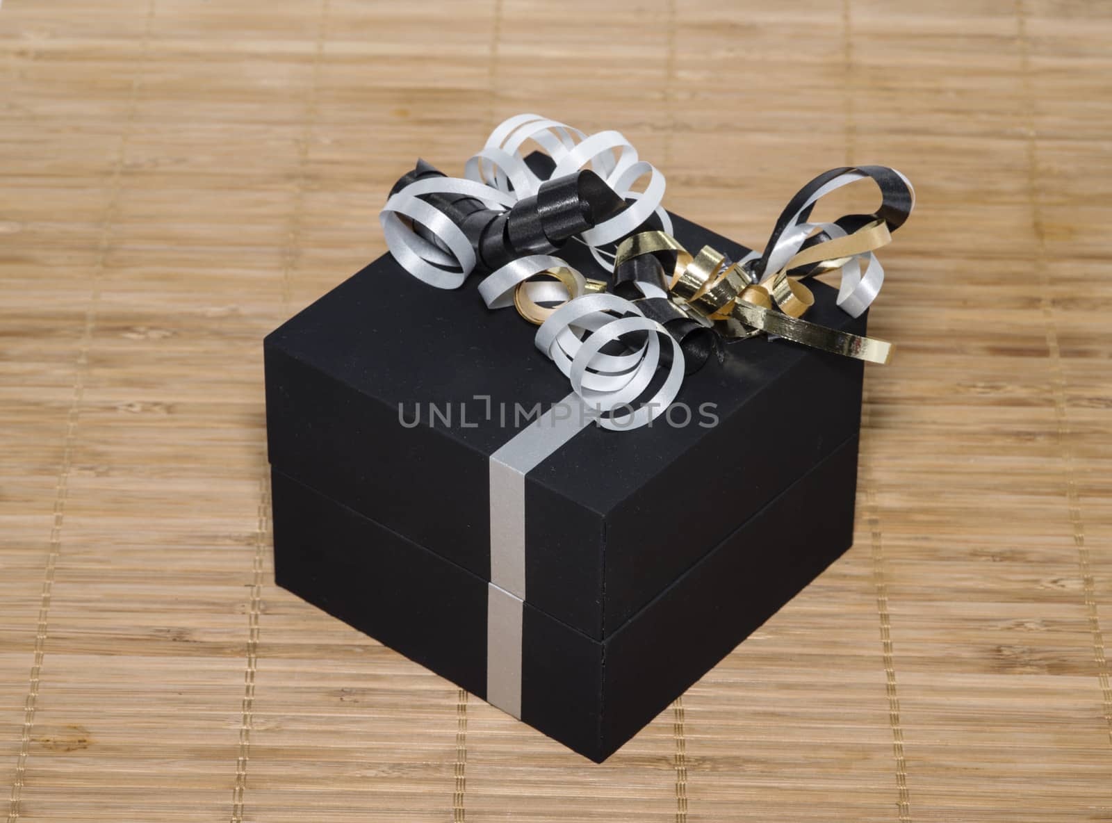 black box with white lines and golden silver bows as present