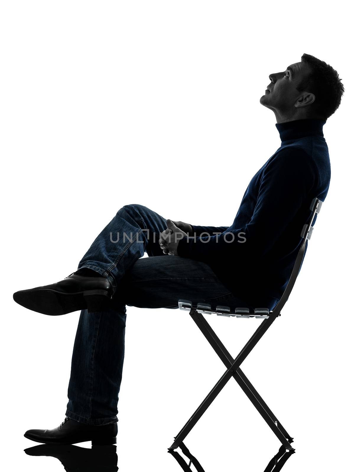 one caucasian man sitting looking up  full length in silhouette studio isolated on white background