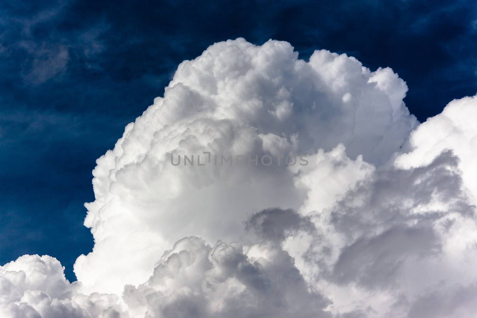 Summer storm thick white clouds cumulous against dark blue sky.