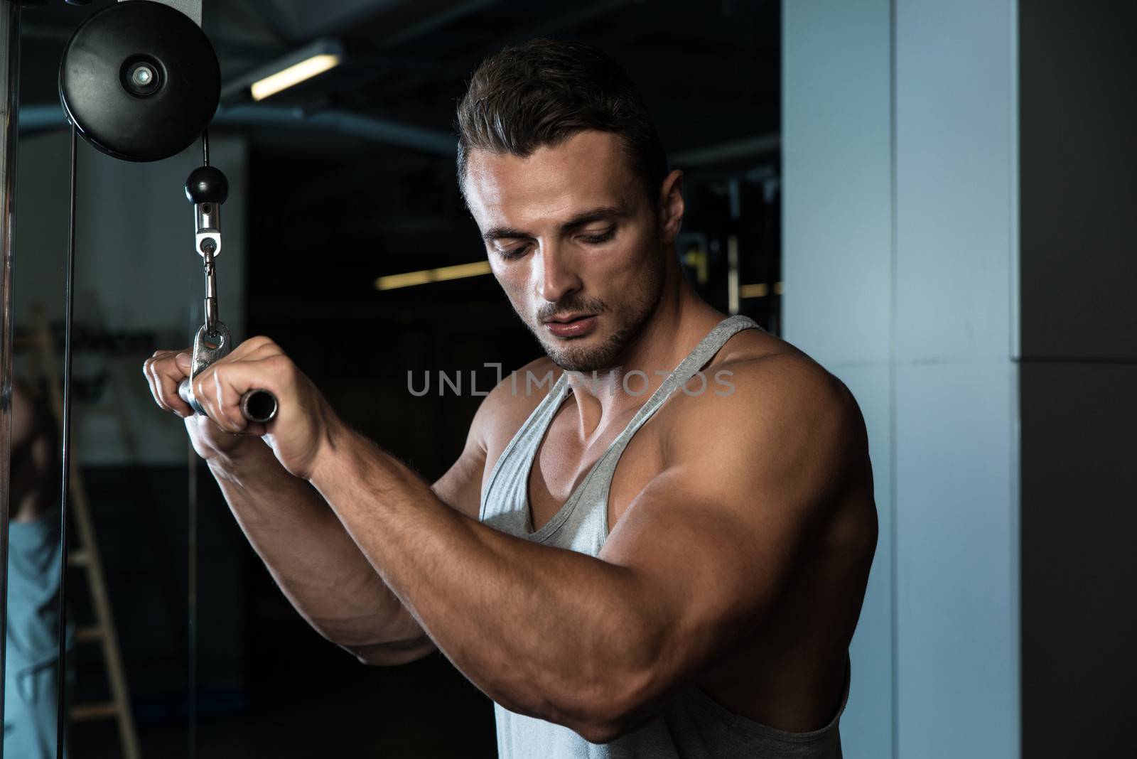 Bodybuilder Doing Heavy Weight Exercise For Triceps With Cable by JalePhoto