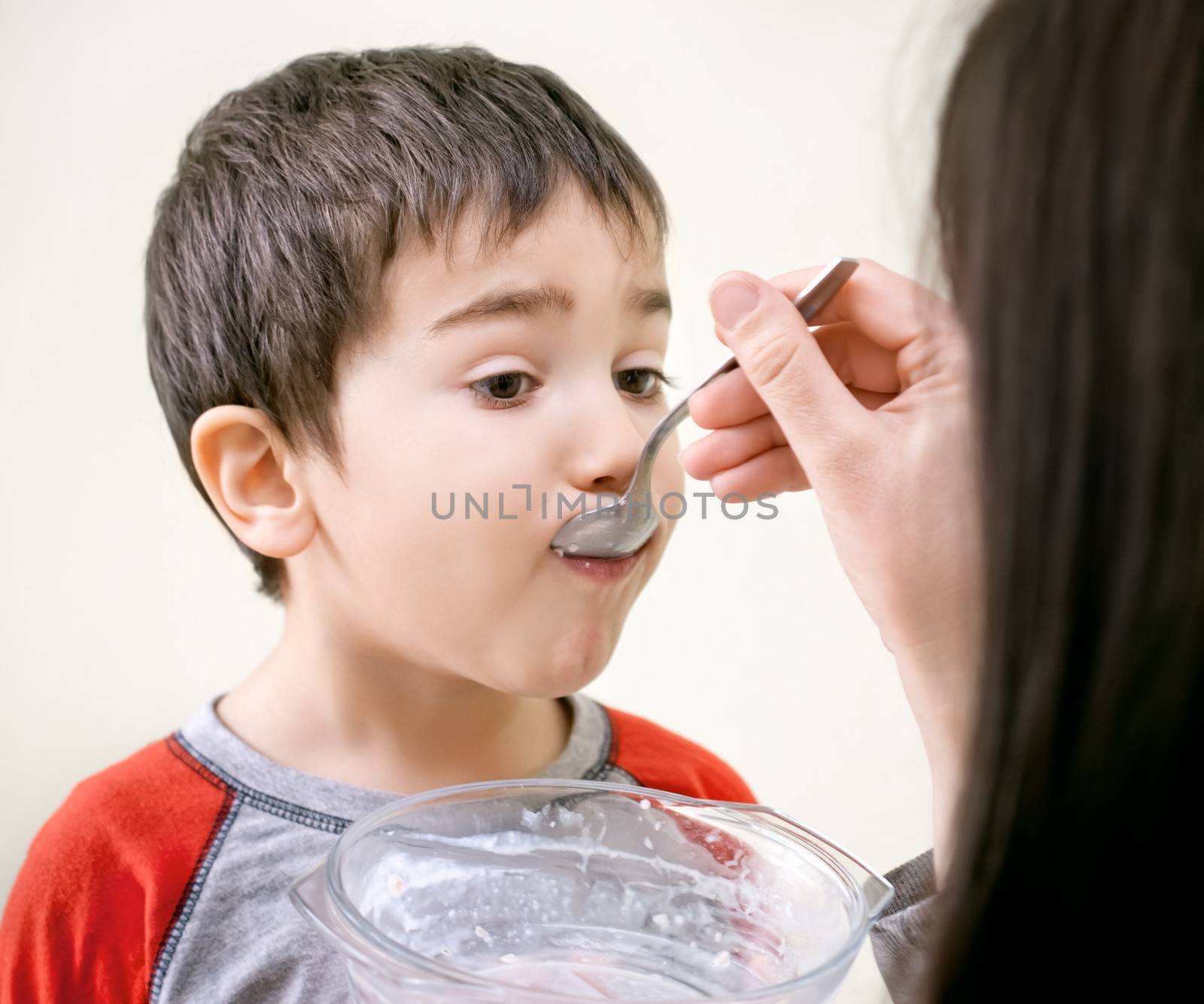  little boy is being fed using spoon by palinchak