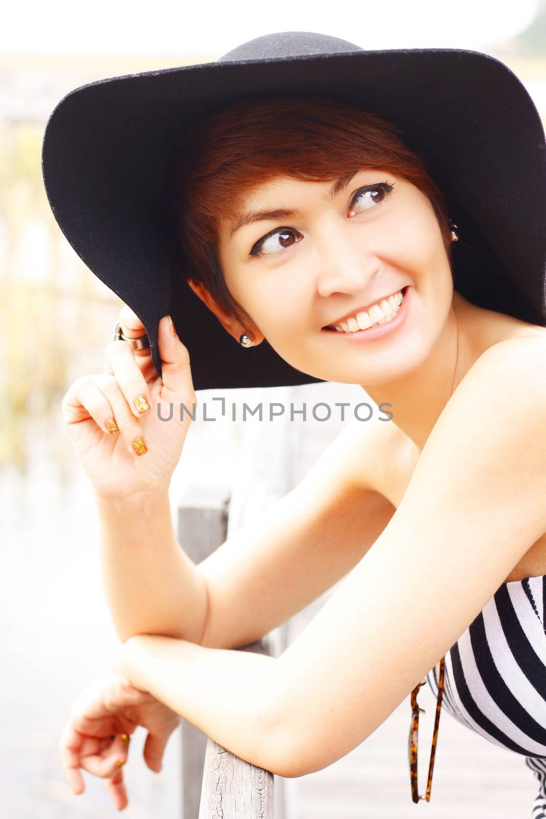 Beautiful Asian woman touches her black hat and look up