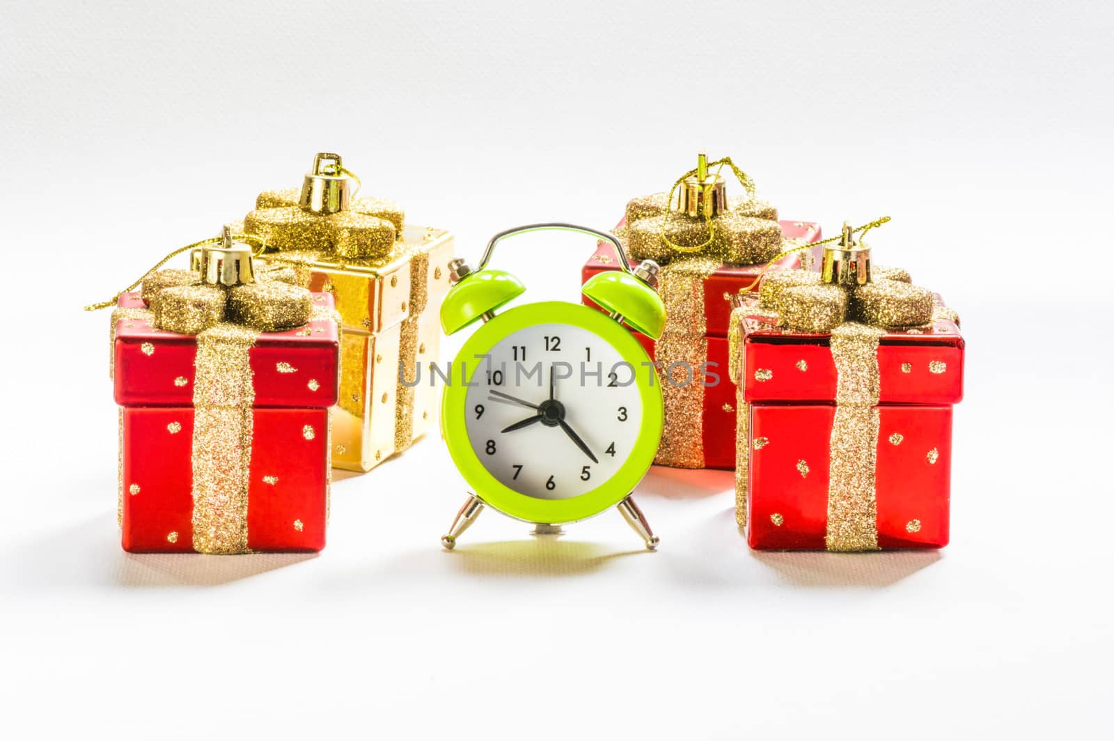 Green alarm clock between present shaped Christmas decorations