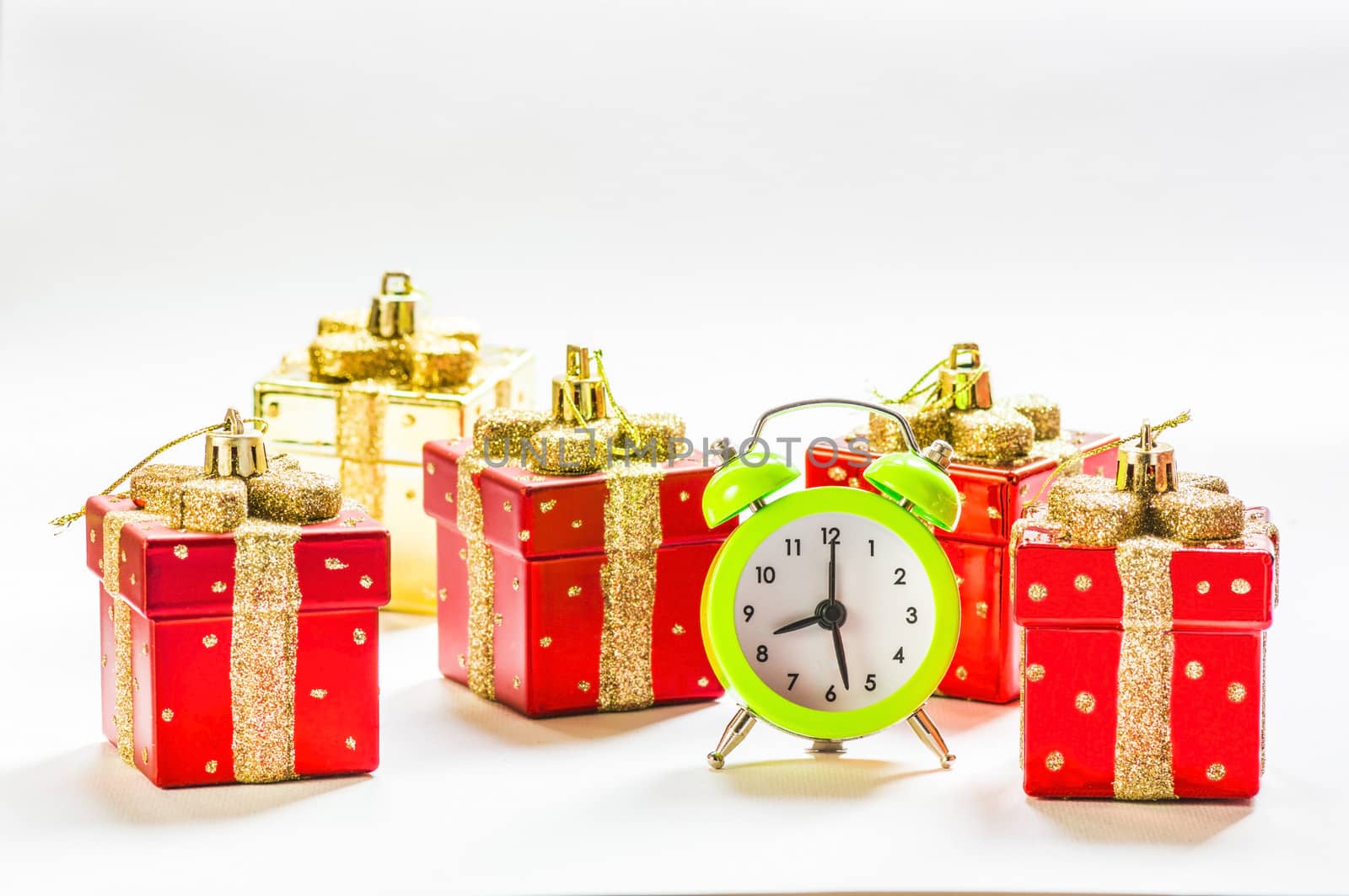 Green alarm clock between present shaped Christmas decorations