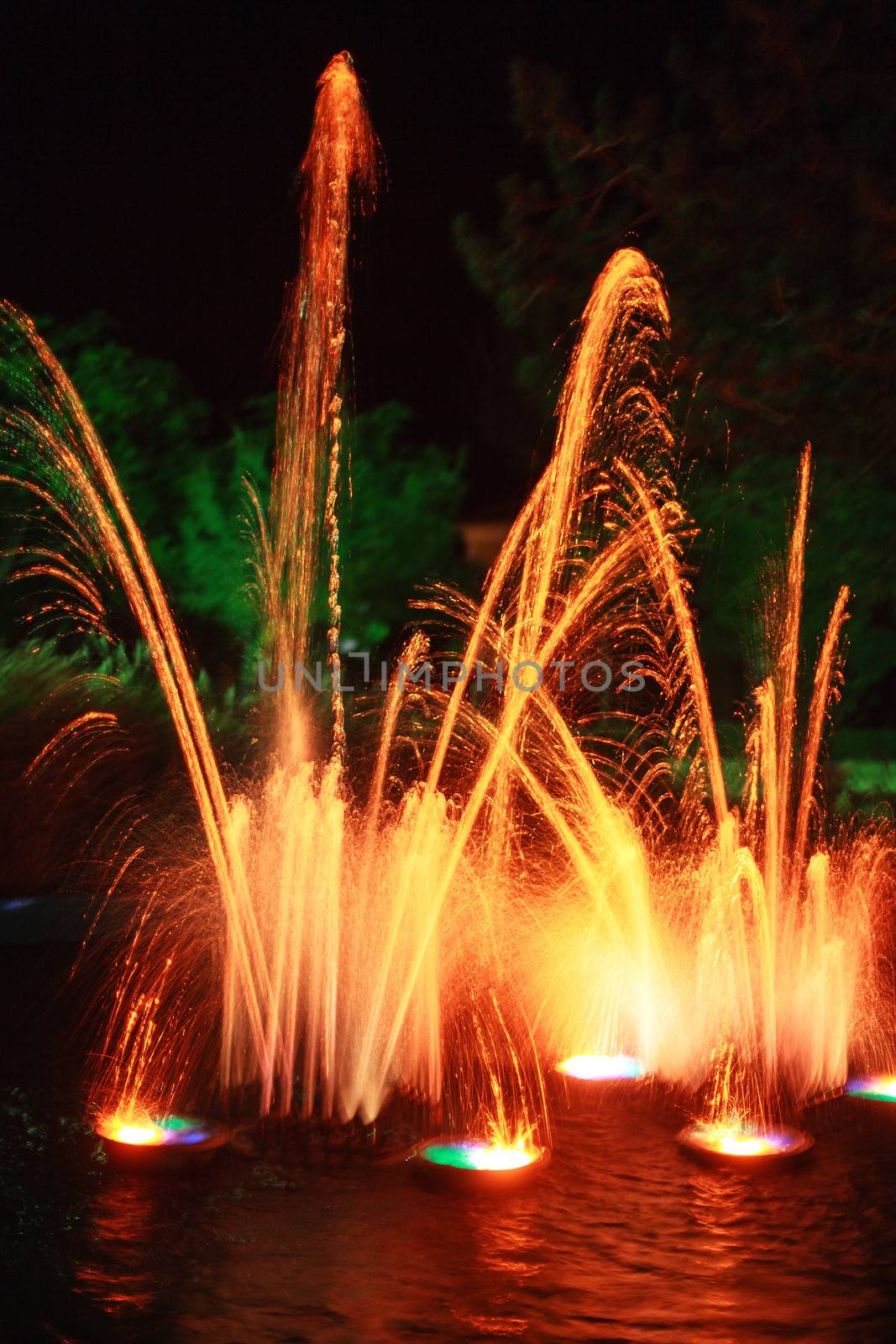 Colourful fiery orange fireworks display with fountains of light on a lake above the water in celebration of a holiday, festival or special event
