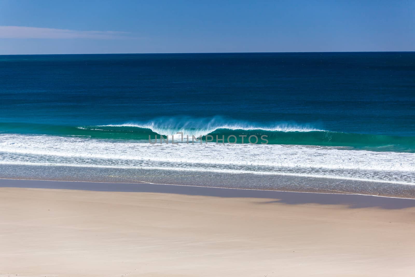 Small ocean waves breaks on white sand beach alone in clean nature environmental landscape.