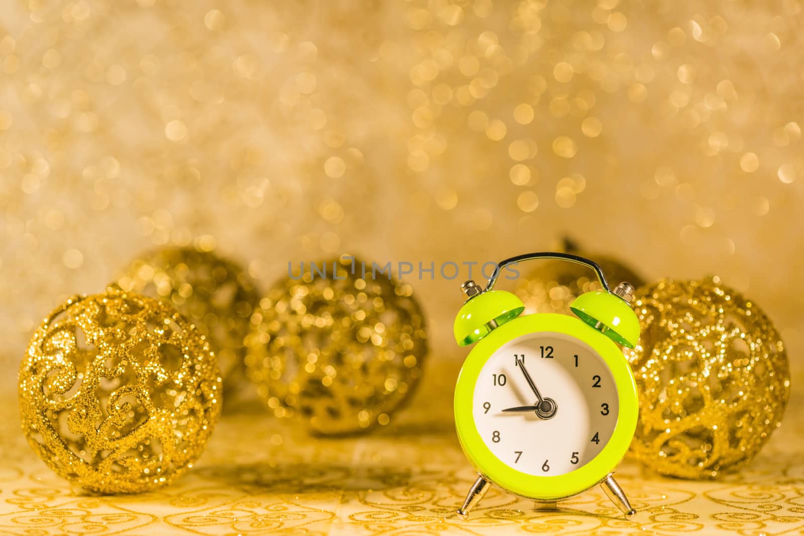 Green alarm clock in front of golden Christmas decorations