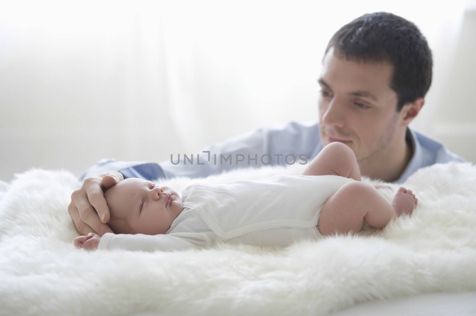Father holds two week old newborn babies head by moodboard