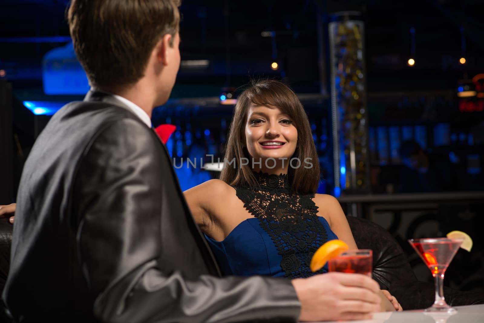 portrait of a woman in a nightclub, sitting on the couch and talking with man