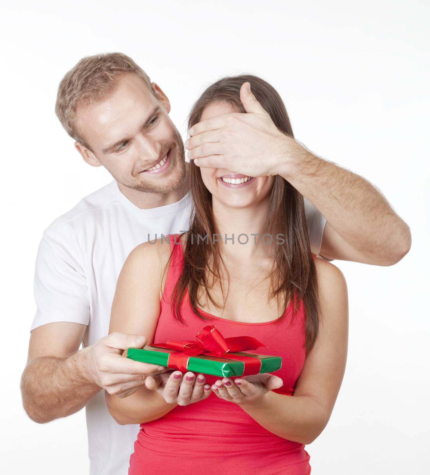 young man covering his girlfriends eyes to give her a surprise present