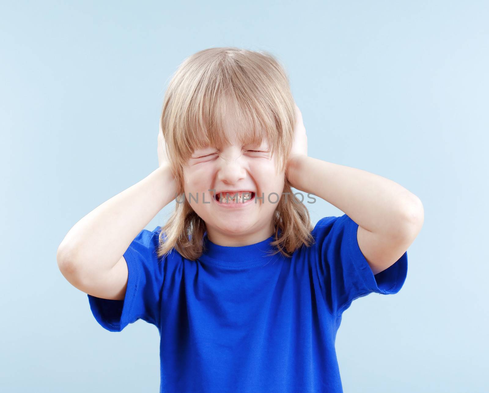 upset boy with long blond hair covering his ears as protection - isolated on blue
