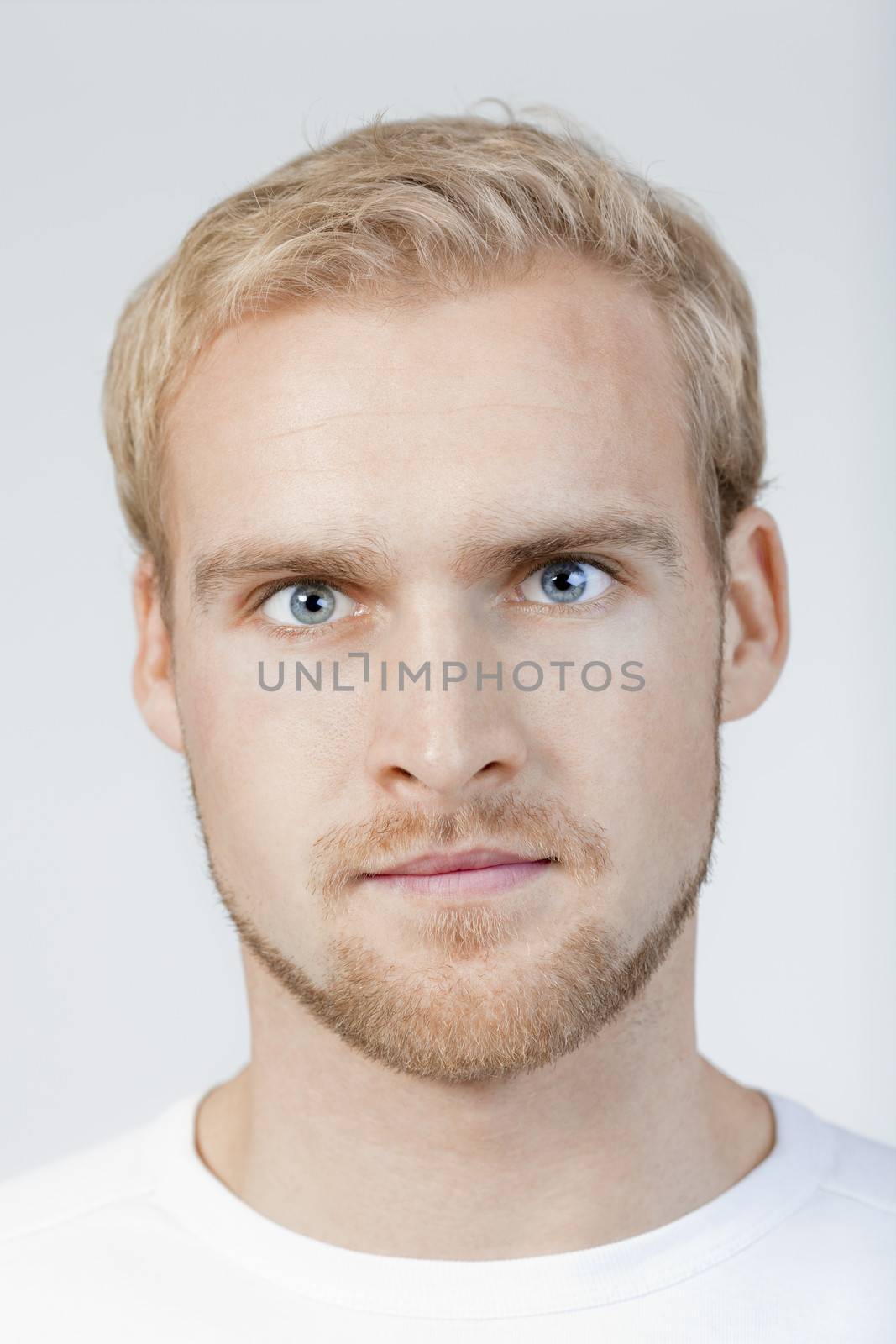 portrait of a young man with blond hair standing- isolated on light gray